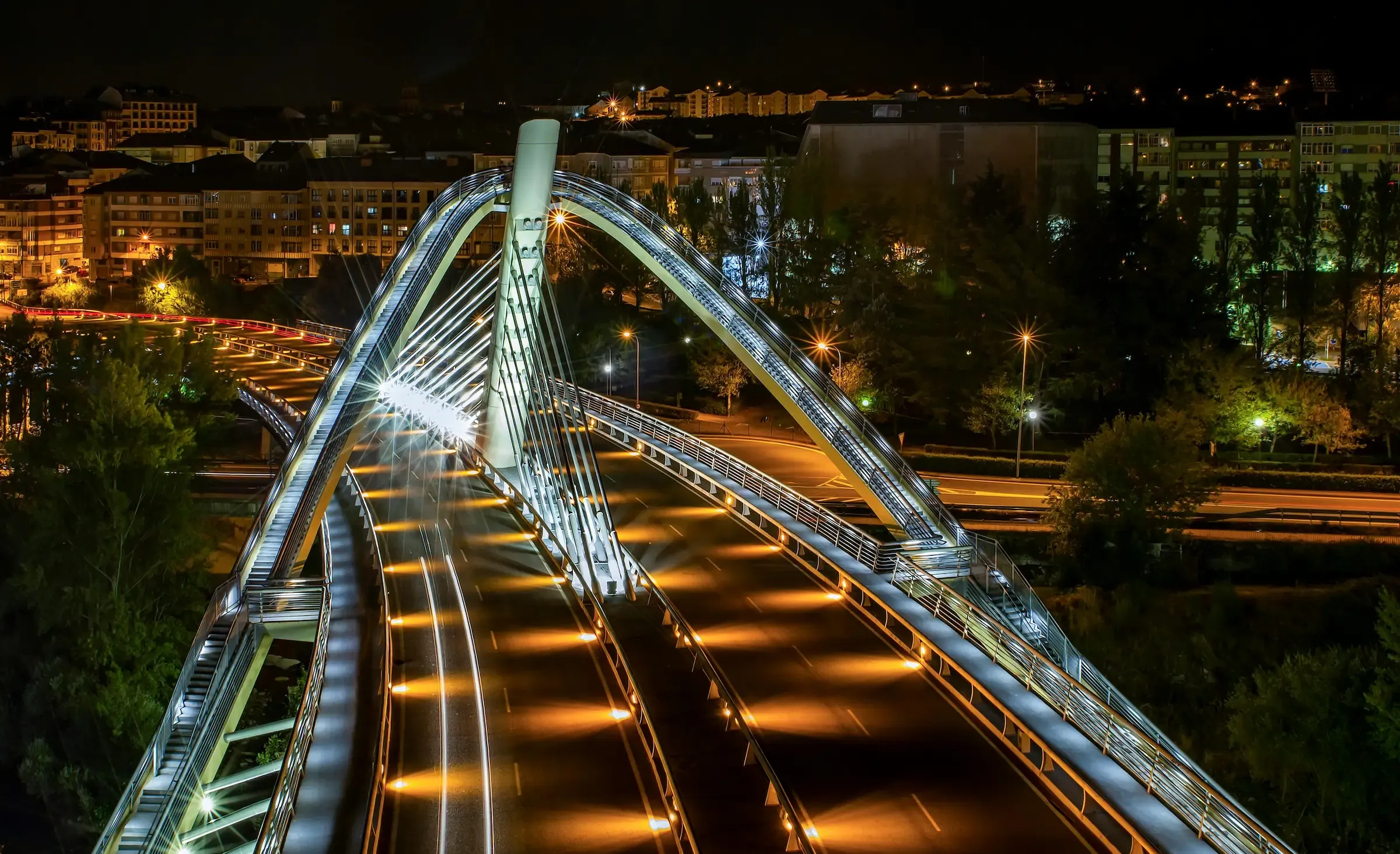 Vista nocturna del Puente del Milenio de Ourense, iluminado, con estelas de luz del tráfico